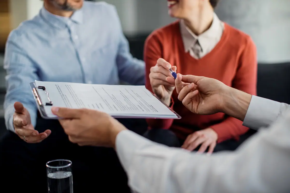 Client signing a document with an attorney