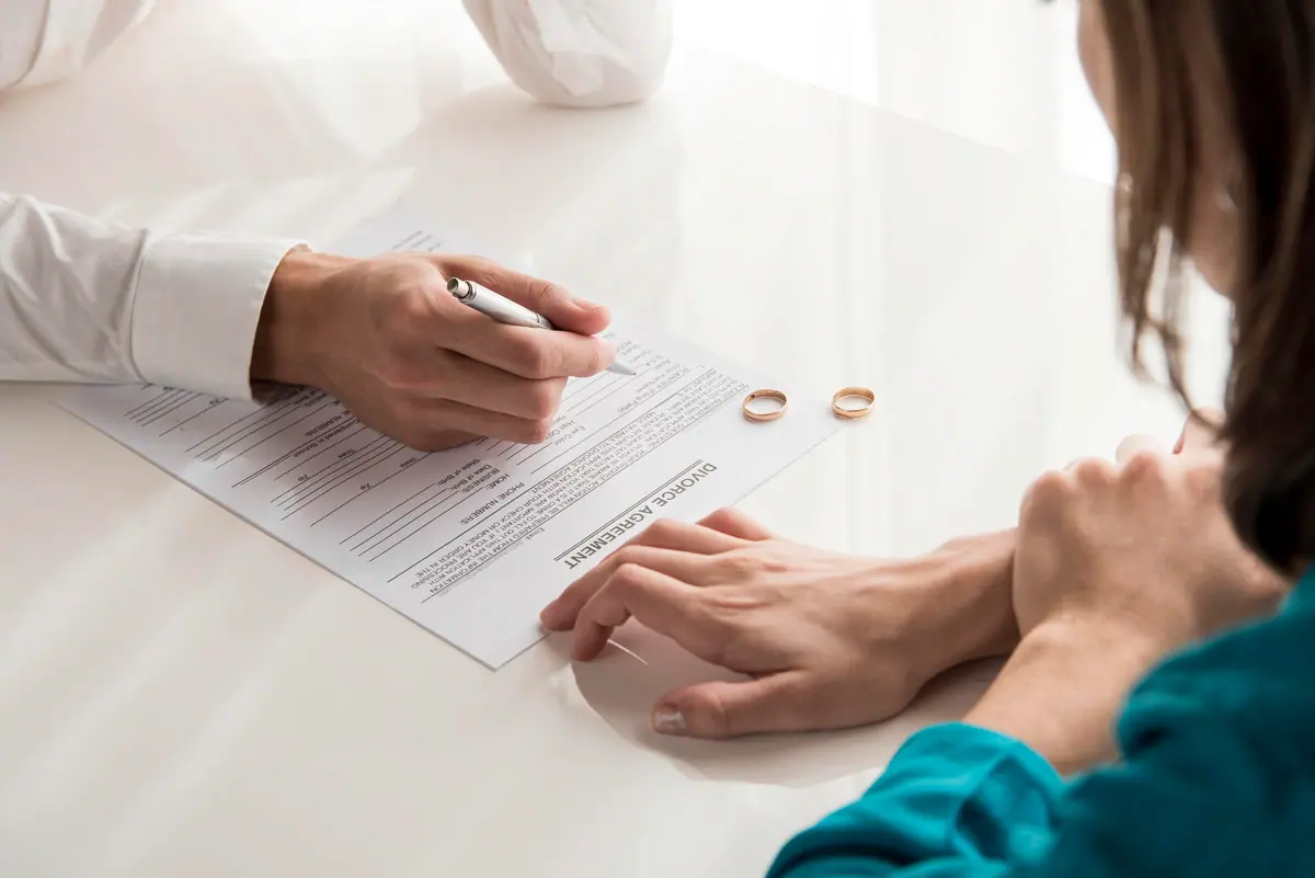 Wedding rings resting on a divorce agreement
