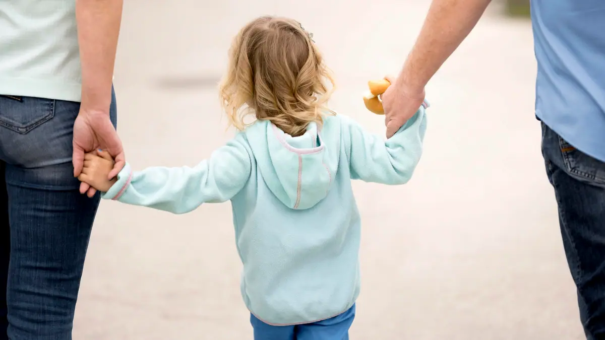 Child holding hands with both parents
