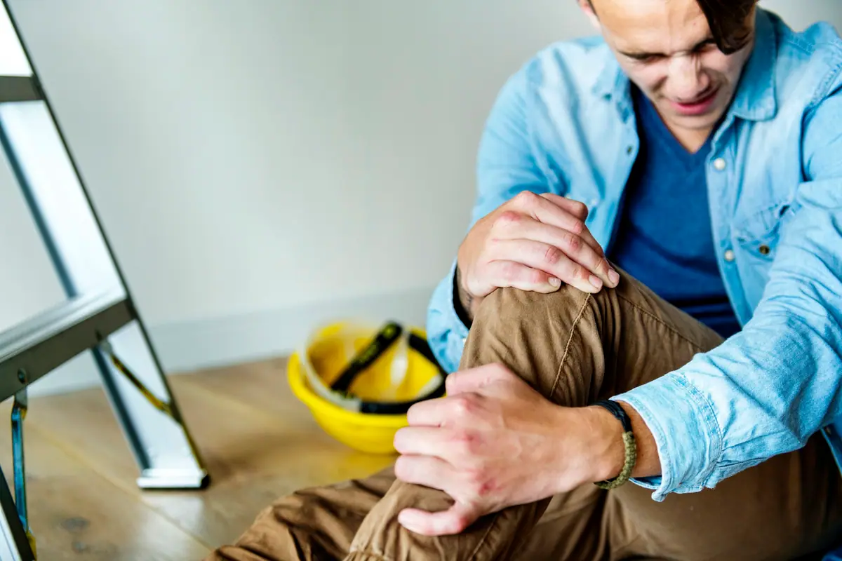 Injured worker holding his knee on a job site